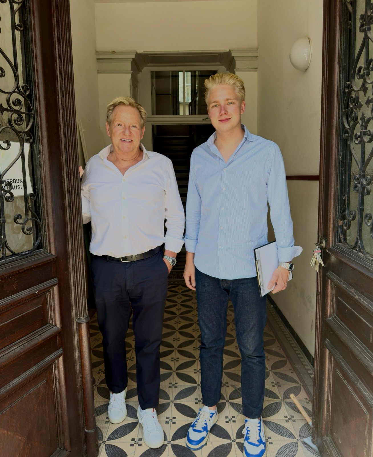 Michael und Glenn Steudel in der geöffneten Haustür eines Düsseldorfer Mehrfamilienhauses